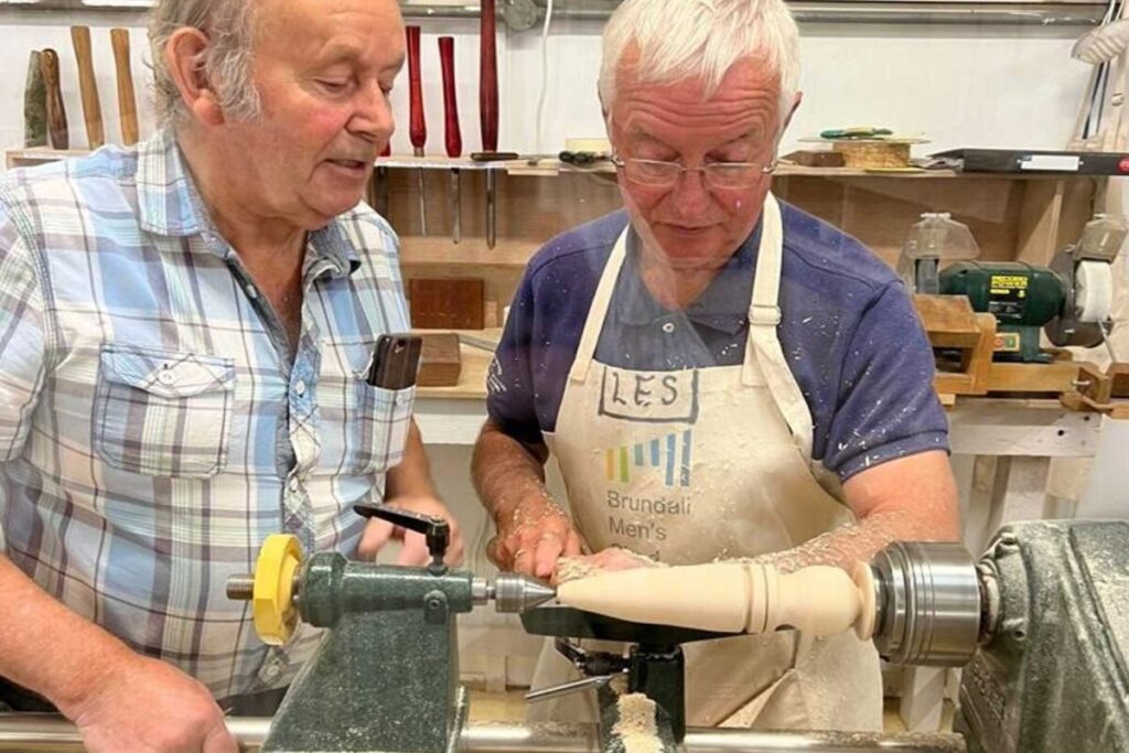 Two men using a wood turning lathe